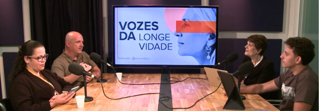 Mesa de gravação em estúdio com microfones e tela exibindo o título “Vozes da Longevidade”.
